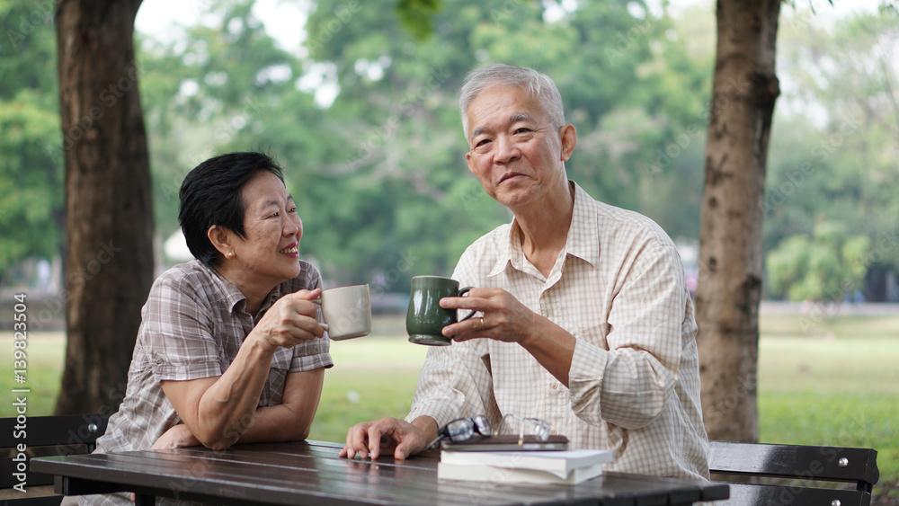 Asian senior couple taking break from learning investment stock fund to drink coffee Asian senior couple taking break from learning investment stock fund to drink coffee