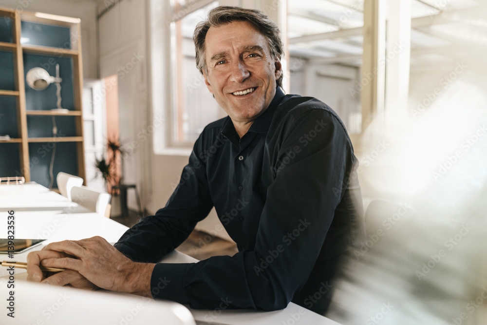 Portrait of smiling mature businessman at table in office Portrait of smiling mature businessman at table in office