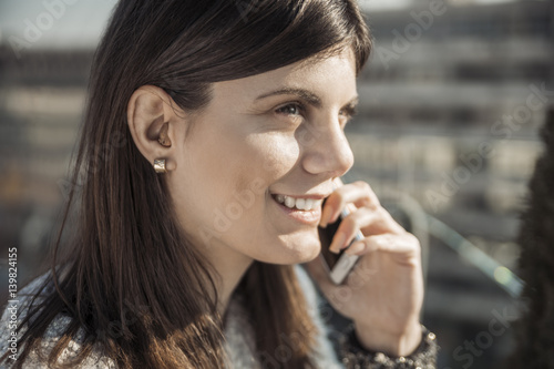 Smiling young woman with hearing aid on the phone photo