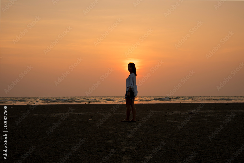 silhouette standing on the beach with sunset background