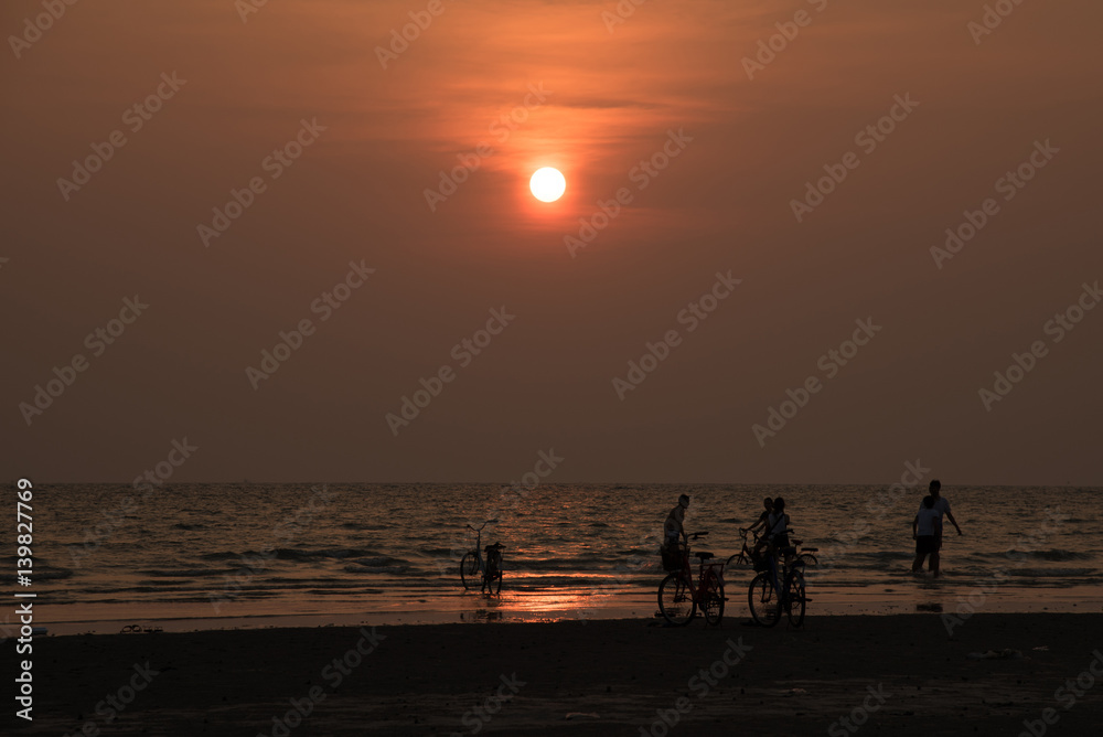 silhouette people playing on beach in the sea on sunset background