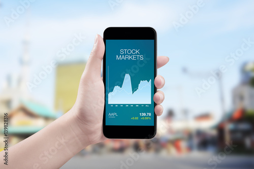 Woman hand holding the phone with stock market money screen.