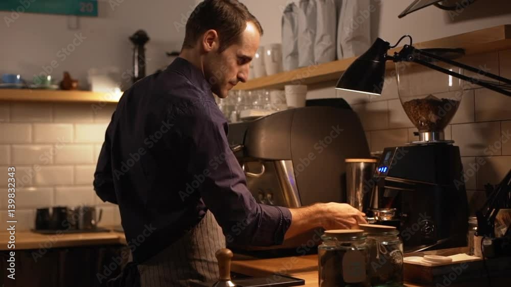 Male smiling Caucasian barista in apron using coffee using grinder and machine in slowmotion Male smiling Caucasian barista in apron using coffee using grinder and machine in slowmotion