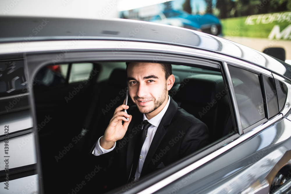 Serious businessman using his phone in his car