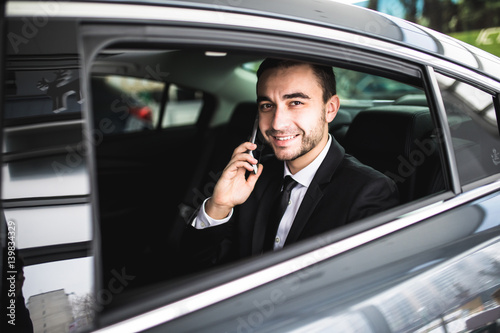 Smile businessman using his phone in his car