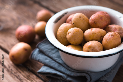 Raw potatoes in a white bowl on a napkin partial blur