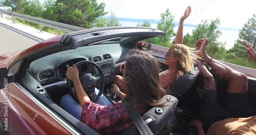 Handsome black man sticking his feet up of convertible riding with his friends