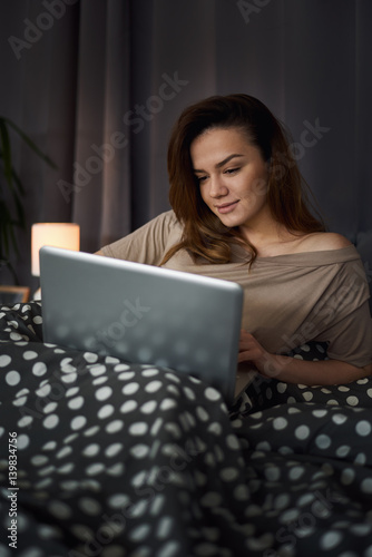 woman using smart phone / laptop at home lying / sitting in bed