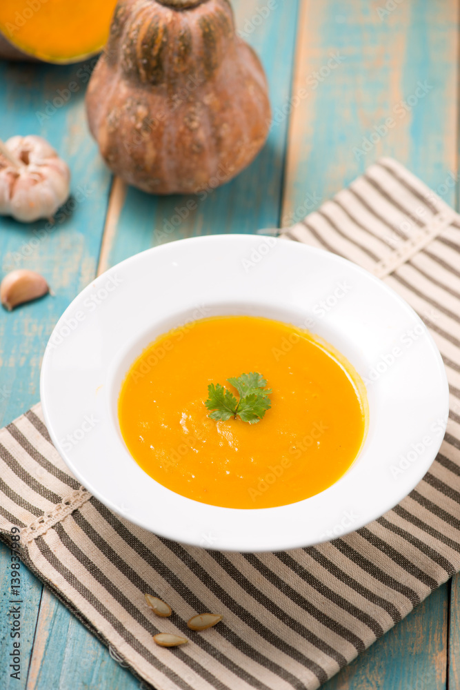 Top view of pumpkin and carrot soup with cream and parsley on blue wooden background. Top view of pumpkin and carrot soup with cream and parsley on blue wooden background.