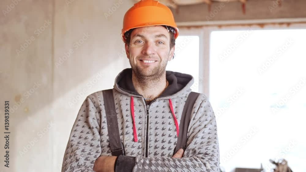 Middle-aged Caucasian male worker wearing orange hard hat standing with folded hands in slowmotion Middle-aged Caucasian male worker wearing orange hard hat standing with folded hands in slowmotion