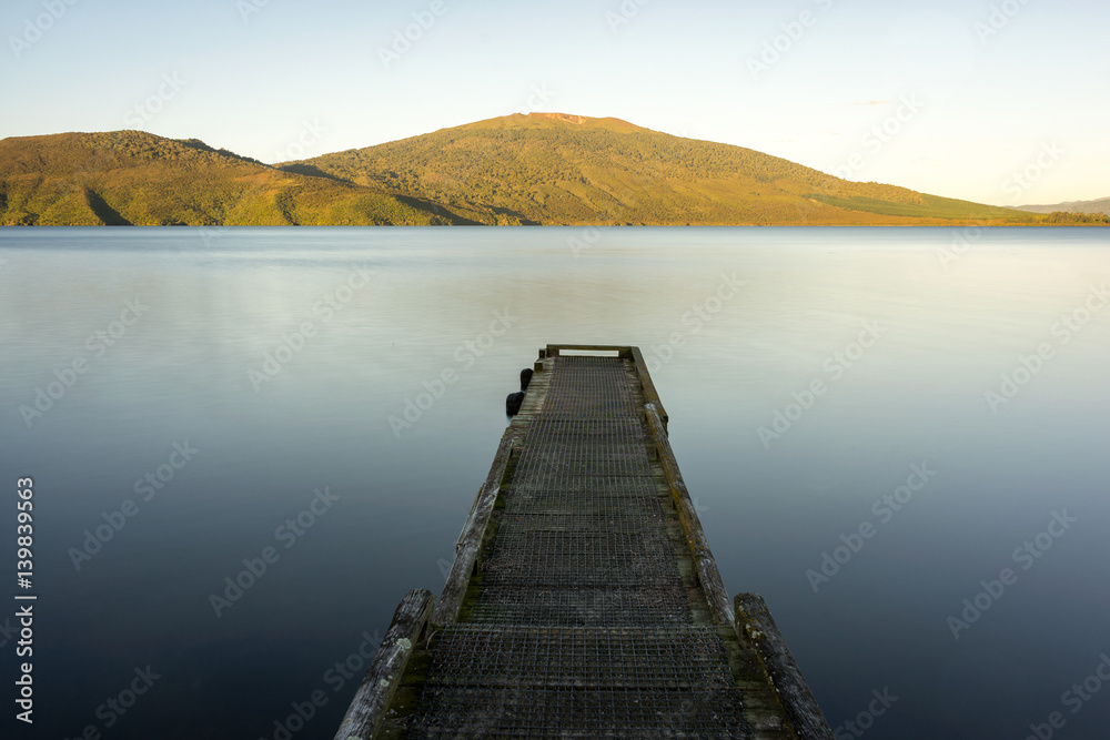 Obraz premium Sunset over the lake with wooden pier.