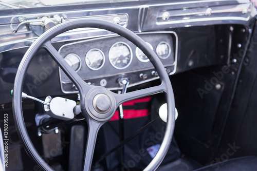 Steering wheel and dashboard in historic vintage car. Retro automobile interior scene. Old vehicle.