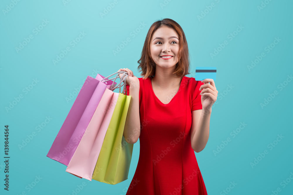 Santa asian woman holding shopping bags and credit card against blue vignette Santa asian woman holding shopping bags and credit card against blue vignette