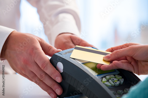 Customer paying with contactless card. NFC technology payment in store. Close Up. Shopping in pharmacy.