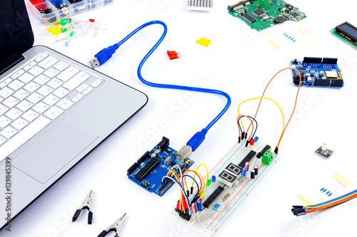 Fotografija Microcontrollers, chips, resistors, usb cables and notebook on white desktop of hardware engineer