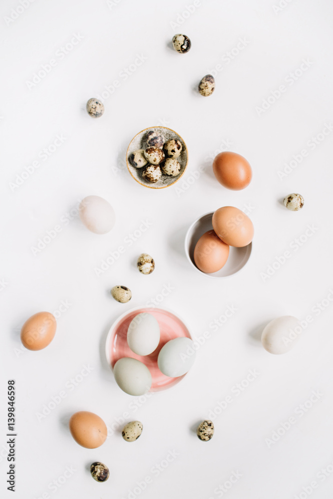 White and brown Easter eggs and quail eggs on white background. Flat lay, top view. Traditional spring concept.