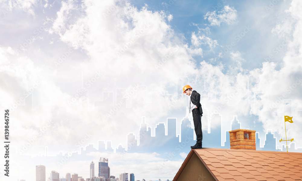 Engineer man standing on roof and looking down. Mixed media Engineer man standing on roof and looking down. Mixed media