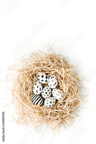 Fancy Easter eggs in nest on white background. Flat lay, top view. Traditional spring concept.