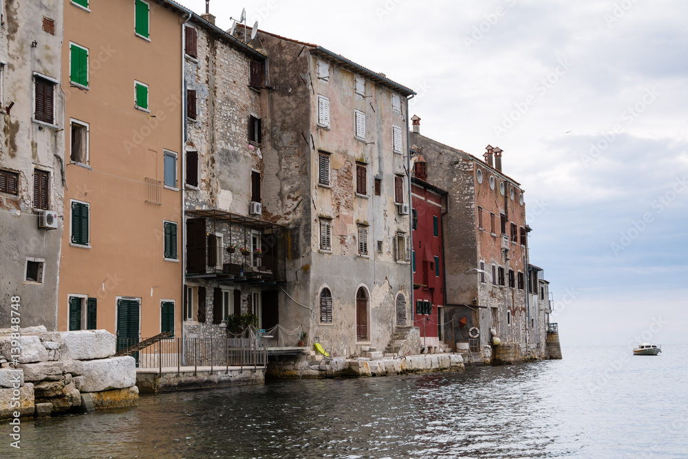 Old houses with facades breaking off directly to the sea in croatian town Rovinj.