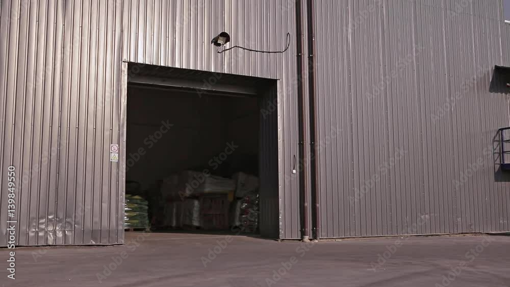 Poland, Lublin - May 2015: Man on a forklift goes out with Large Warehouse sunny weather in the yard Poland, Lublin - May 2015: Man on a forklift goes out with Large Warehouse sunny weather in the yard
