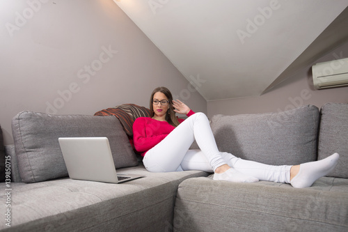 Beautiful woman relaxing at home using laptop.