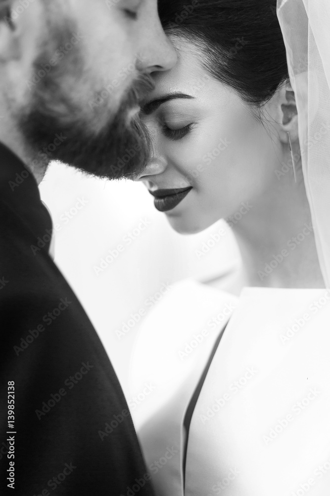 elegant stylish groom gently embracing gorgeous bride in light. unusual wedding couple in retro style. romantic moment. black white photo