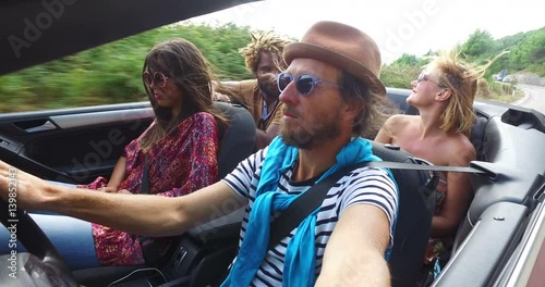 Bearded hipster man with a hat driving his friends in convertible