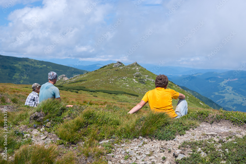 Fototapeta premium Hiker, man sitting on an alpine meadow next to his friends