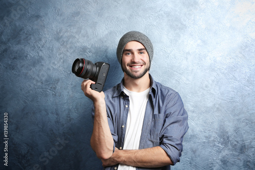 Handsome young photographer near grey textured wall photo