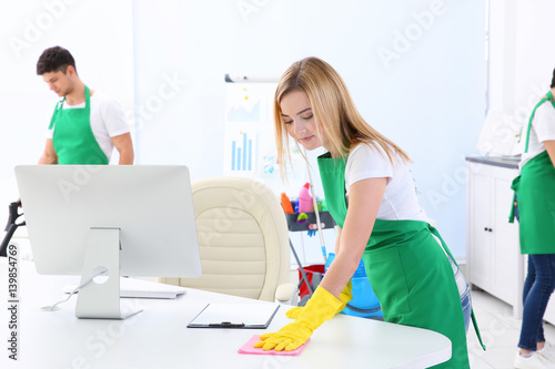 Young woman cleaning office...