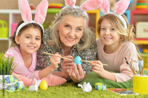 Grandmother and two granddaughters paint Easter eggs