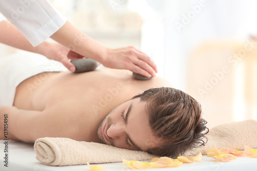 Young man having stones massage in spa salon