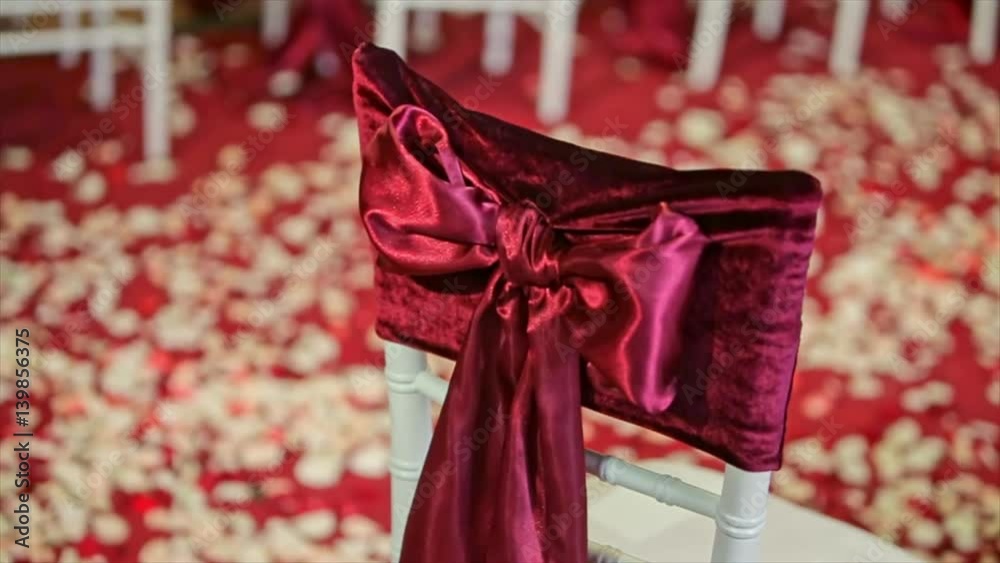 Beautiful fabric bow on the chair. Wedding restaurant for marriage. White decor for bride and groom. Colorful decoration for celebration. Beauty bridal interior Beautiful fabric bow on the chair. Wedding restaurant for marriage. White decor for bride and groom. Colorful decoration for celebration. Beauty bridal interior