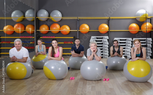 People of different ages training with fit balls in gym