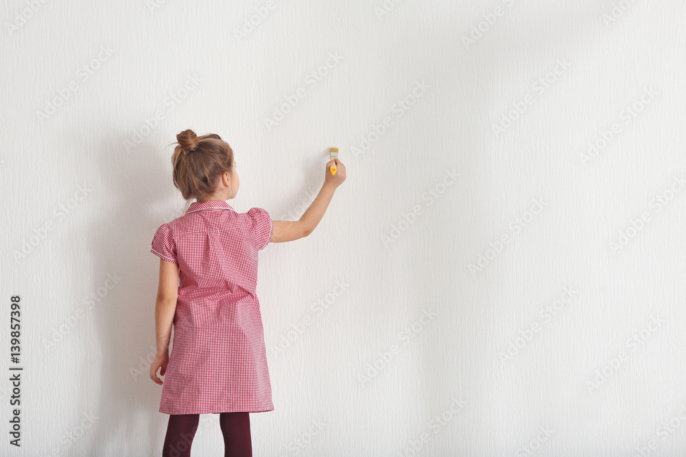 Obraz premium Cute little girl painting on light wall