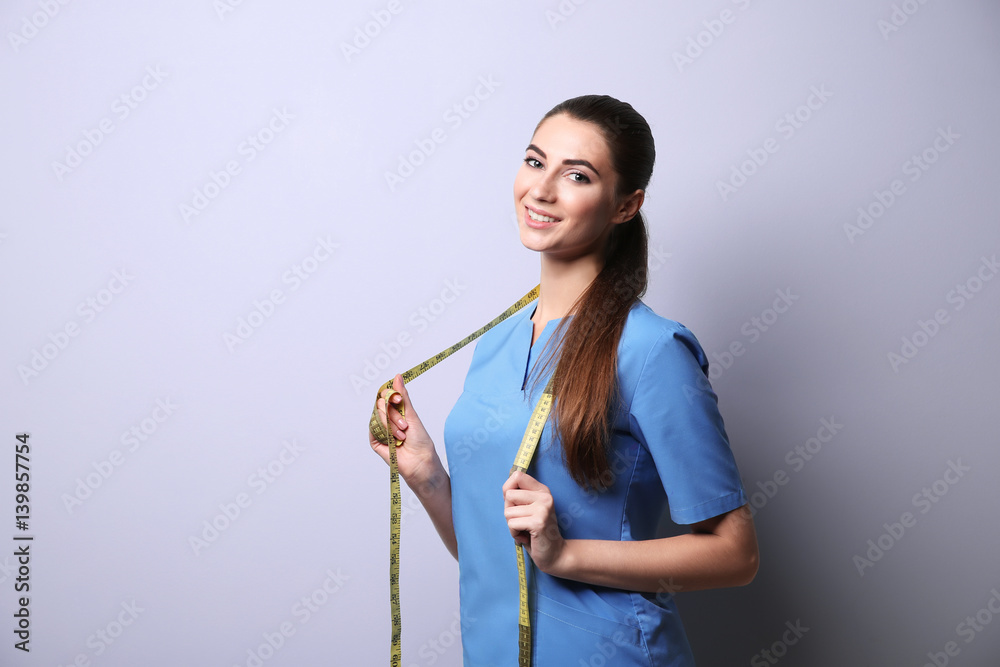 Young female nutritionist on light color background Young female nutritionist on light color background