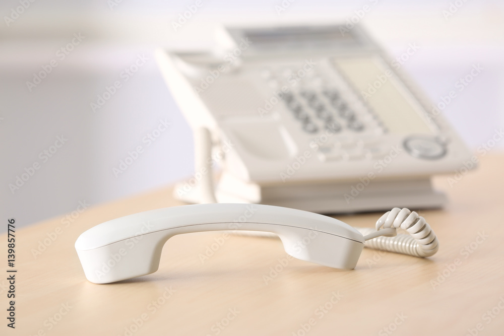 Telephone with picked up receiver on wooden table in office Telephone with picked up receiver on wooden table in office