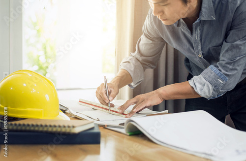 Engineer concept : Architect working on blueprint.engineer inspective in workplace , laptop ,calculator, blueprints,helmet. photo