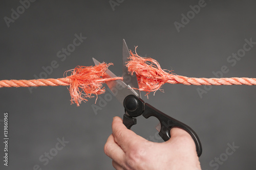 Rotes Seil wird zerschnitten / Rotes Seil wird mit einer Schere zerschnitten.