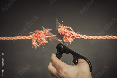 Rotes Seil wird zerschnitten / Rotes Seil wird mit einer Schere zerschnitten. photo