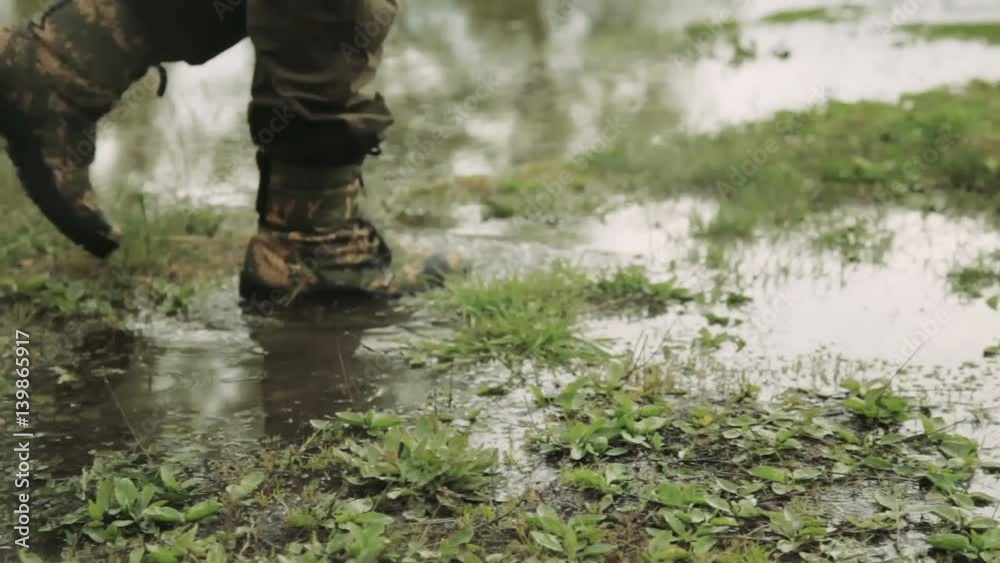A man in army boots. The hunter walks in khaki boots. The soldier overcomes obstacles