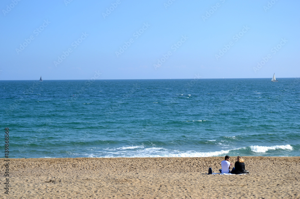 Couple assis sur la plage au bord de la mer