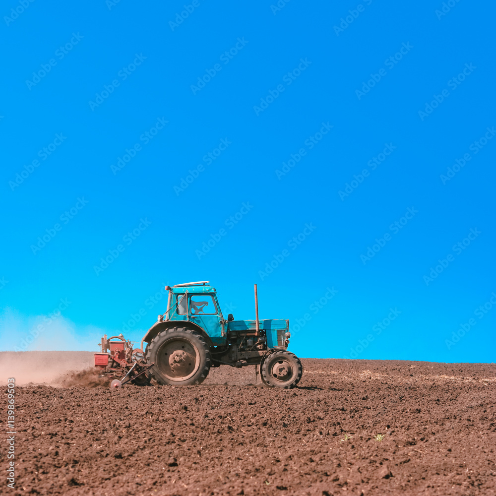 Fototapeta premium Tractor cultivating field at spring. Russian agriculture