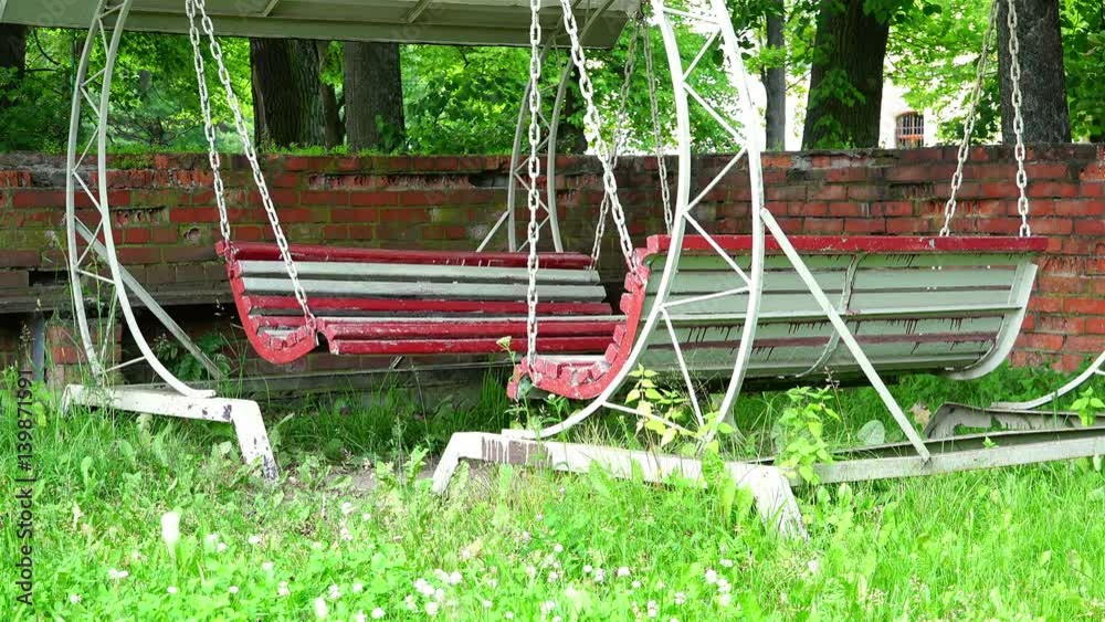 Wooden dilapidated swings of circular shape in an iron canvas under a covered canopy Wooden dilapidated swings of circular shape in an iron canvas under a covered canopy