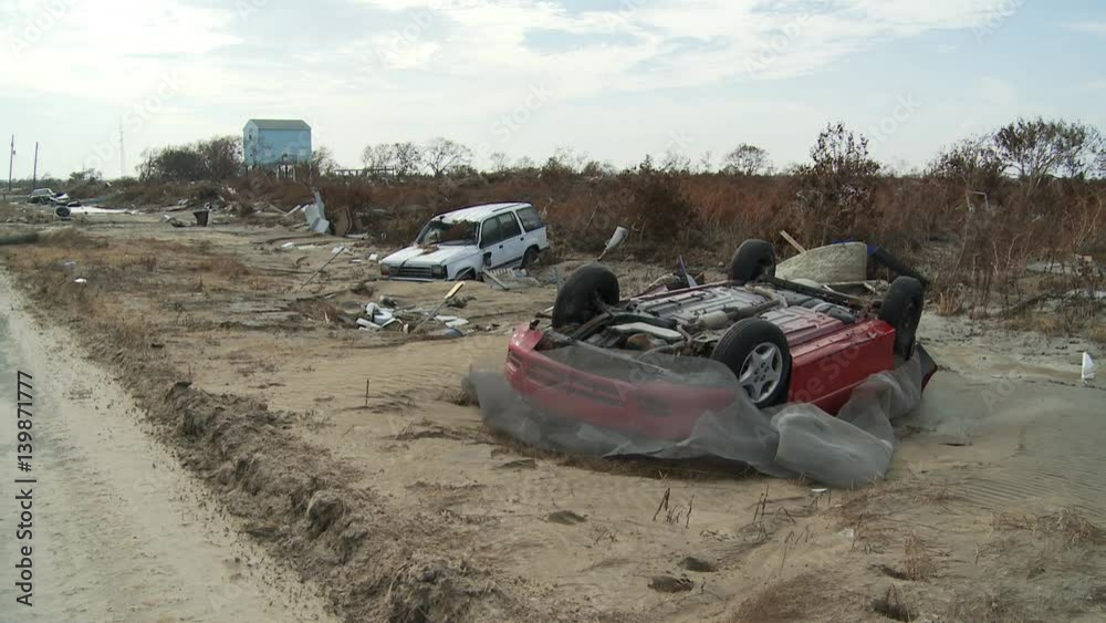 Wrecked cars lying in debris-strewn sand after hurricane Wrecked cars lying in debris-strewn sand after hurricane