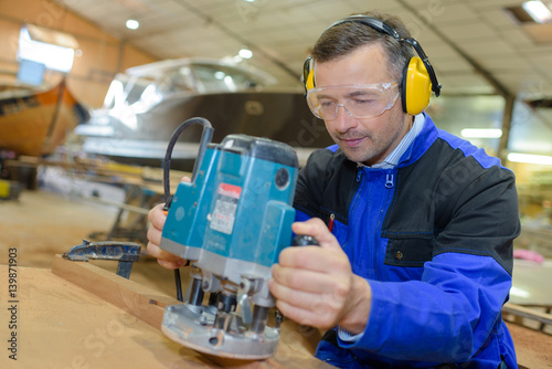 worker sanding wood in boatyard photo