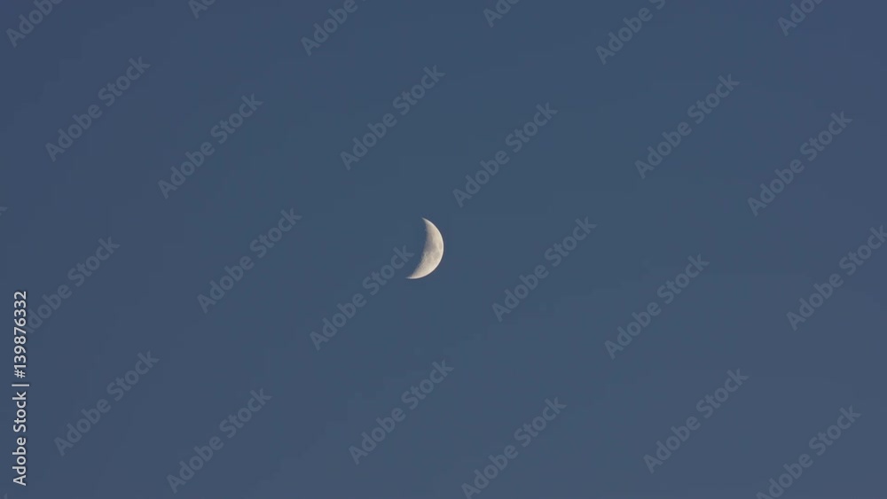 Young moon rise on darkening blue sky Young moon rise on darkening blue sky