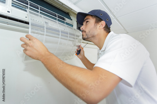 portrait of mid-adult male technician repairing air conditioner