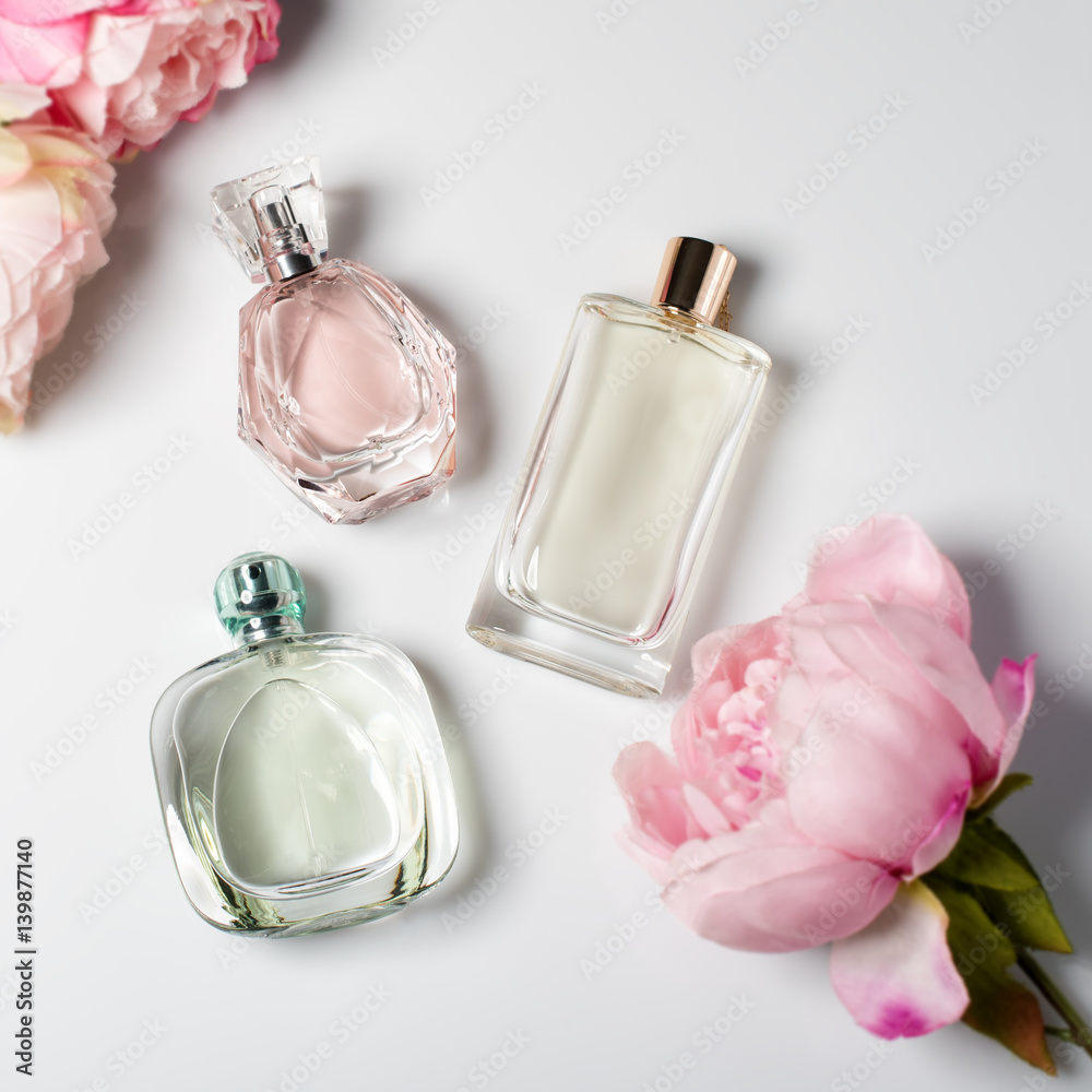 Perfume bottles with flowers on light background. Perfumery, cosmetics, fragrance collection. Flat lay Perfume bottles with flowers on light background. Perfumery, cosmetics, fragrance collection. Flat lay