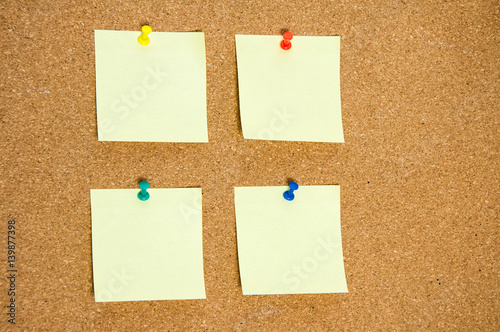 A few blank yellow stickers for taking notes on a cork board close-up.